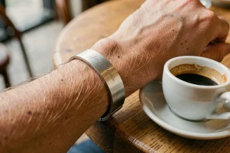 Bracelet homme en acier brossé avec gravure personnalisée porté au poignet dans un café